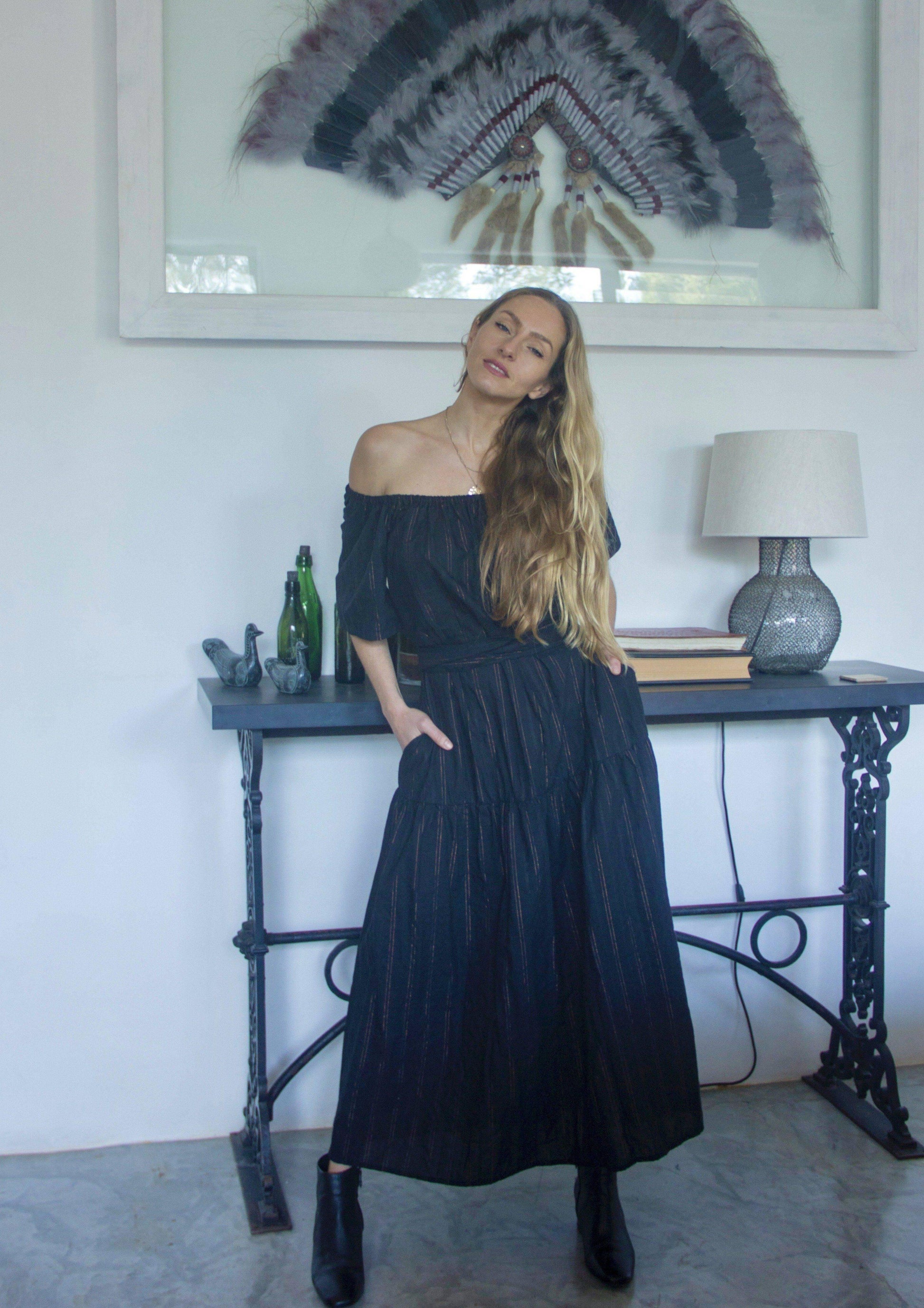 ADÈLE DRESS • Soft cotton maxi length dress featuring off-shoulder neckline, wrap-around belt, and side pockets in black with contrast fine copper fleck stripes. Available in one size.