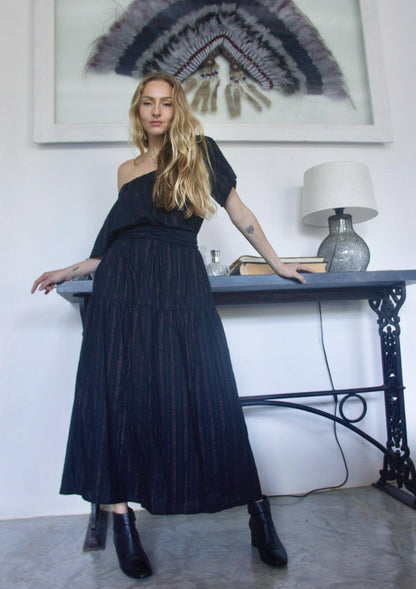 ADÈLE DRESS • Soft cotton maxi length dress featuring off-shoulder neckline, wrap-around belt, and side pockets in black with contrast fine copper fleck stripes. Available in one size.